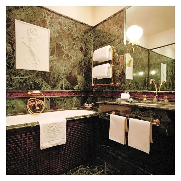 Luxuriöses Badezimmer mit grünen Marmordetails und hochwertigen Armaturen