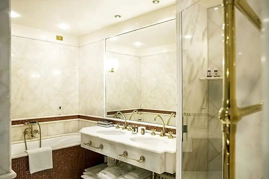 Badezimmer mit eleganter weißer Marmoreinrichtung und goldenen Akzenten