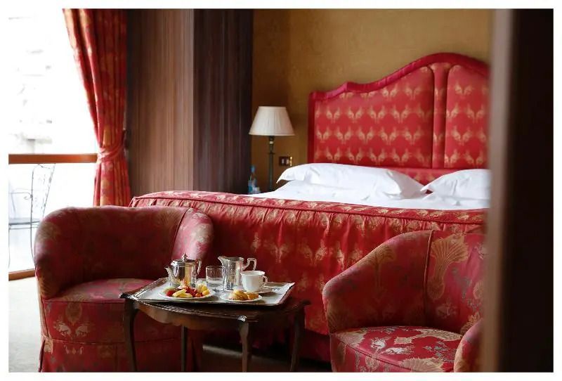 Luxuriöses Zimmer mit rötlichen Akzenten und gemütlicher Sitzecke.