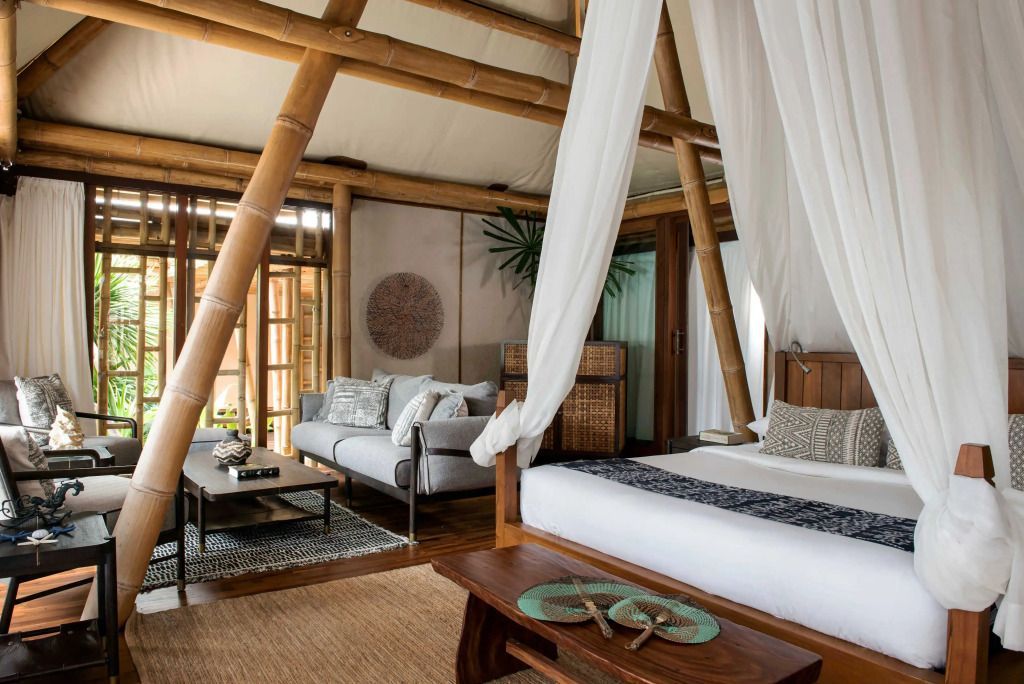 Innenraum einer Deluxe Villa mit Himmelbett und eleganter Sitzecke aus Bambus