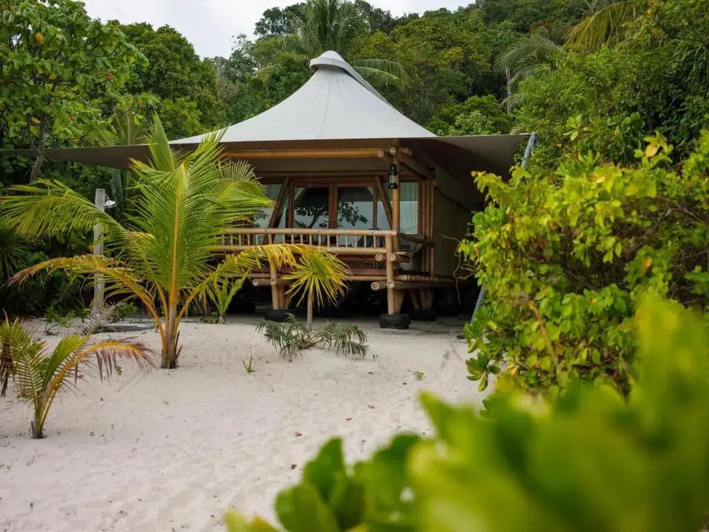 Luxuriöse Suite im tropischen Stil mit Bambus und Blick auf den Sandstrand.