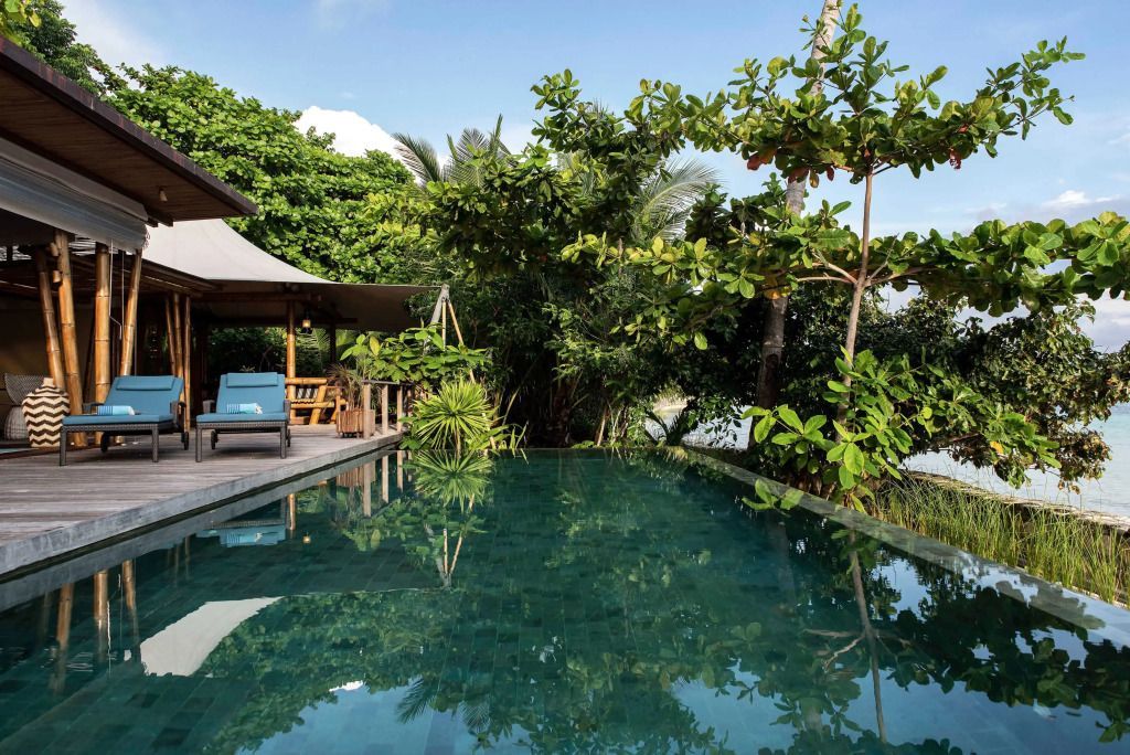 Privater Pool einer Villa mit üppiger tropischer Vegetation im Hintergrund