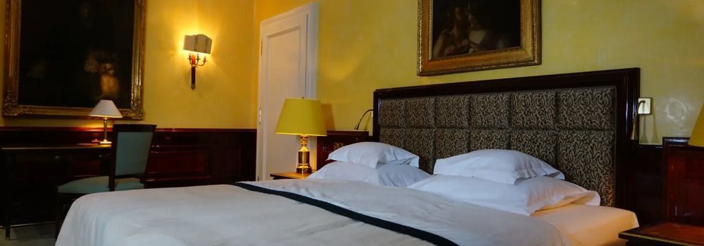 Elegantes Schlafzimmer mit gelbem Wandanstrich und Gemälde in der Suite des Hotels.
