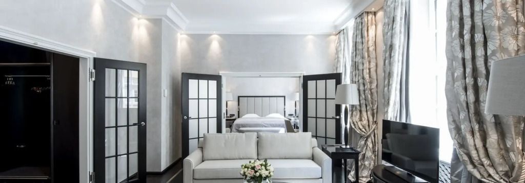 Elegantes Hotelzimmer mit Sofa, Blumenstrauß und luxuriösem Bett im Hintergrund