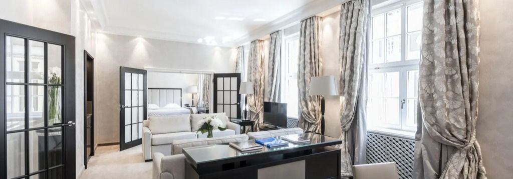 Elegante Hotelsuite mit hellen Möbeln und stilvollen Vorhängen