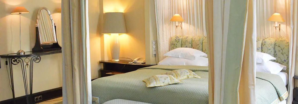 Gemütliches Bett mit dekorativen Kissen und stimmungsvoller Beleuchtung in der Bavarian Suite