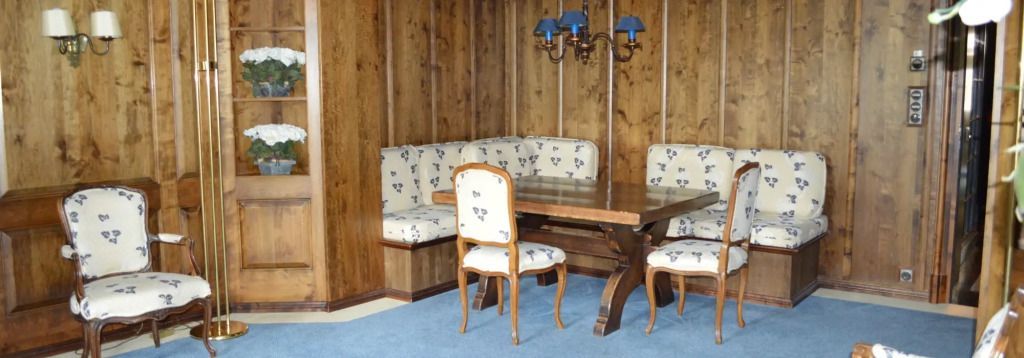 Elegantes Esszimmer mit Holzwänden und blumig gepolsterten Sitzen