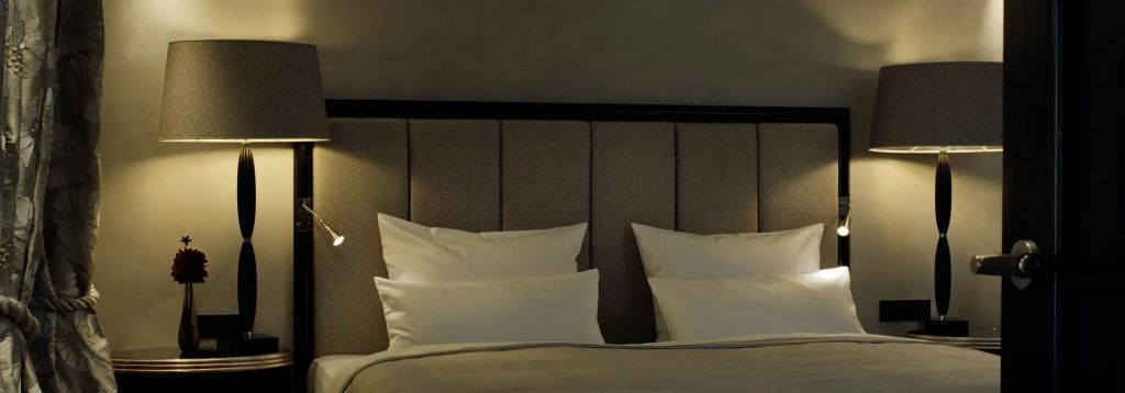 Schlafzimmer mit eleganten Kissen und dezenter Beleuchtung in Grautönen