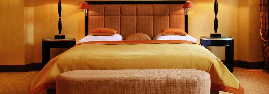 Luxuriöses Schlafzimmer in der Graf Pilati Suite mit orangefarbenem Kopfteil und Kissen