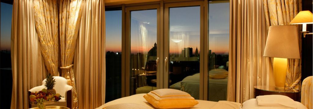 Abendansicht vom Schlafzimmer auf die Stadt bei Sonnenuntergang mit großen Fenstern
