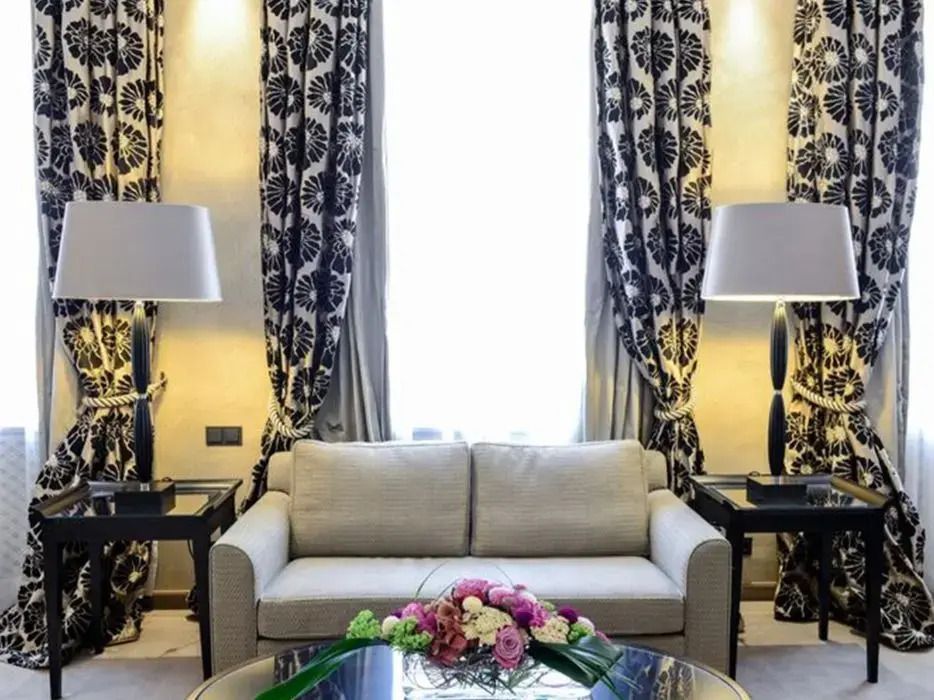 Elegantes Wohnzimmer mit beigen Sofa und floralen Vorhängen in der Junior-Suite