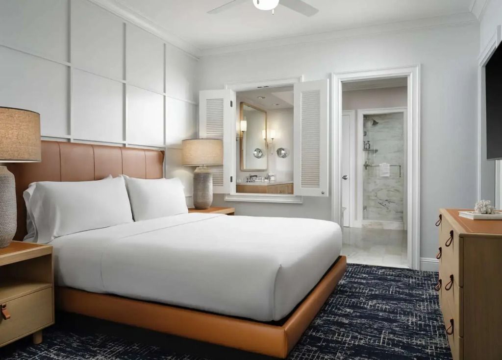 Helles Schlafzimmer mit großen Betten und direktem Zugang zum Badezimmer.