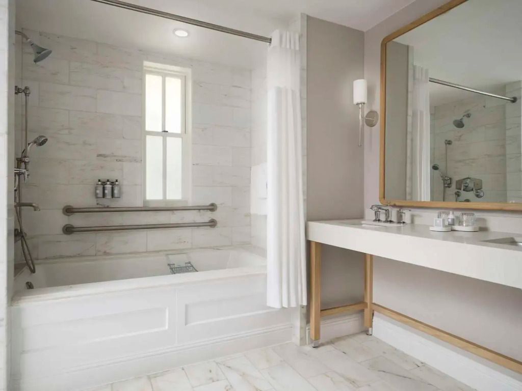 Elegantes Bad mit Marmorfliesen, Badewanne und großem Spiegel