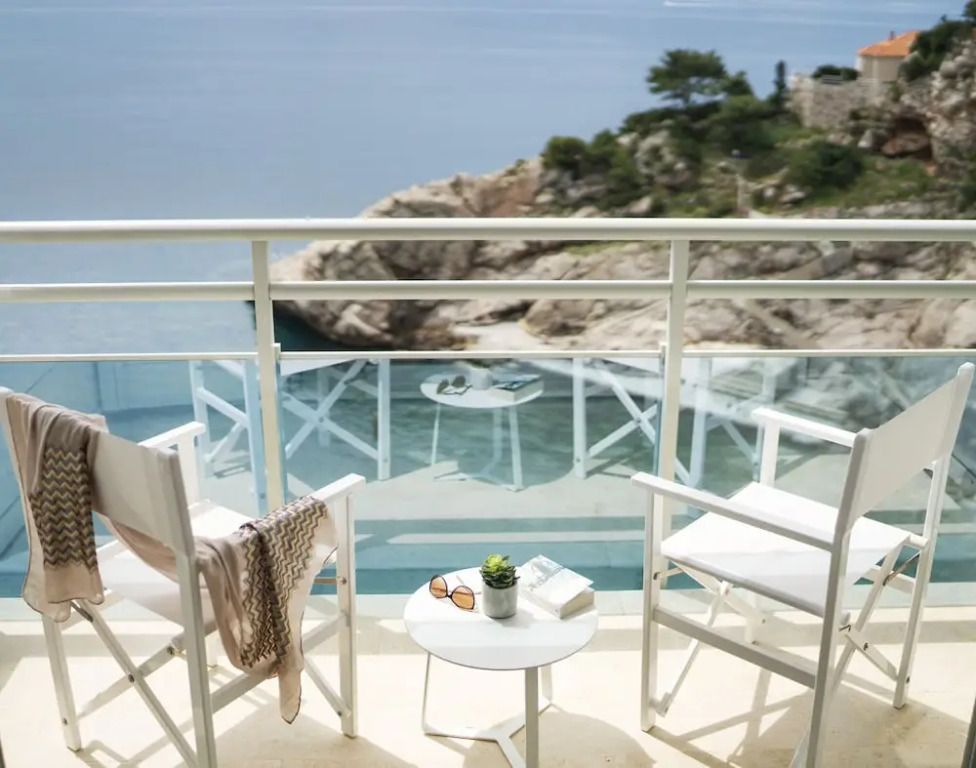 Balkon mit Blick auf das Meer und Felsenlandschaft mit zwei Stühlen und einem Tisch
