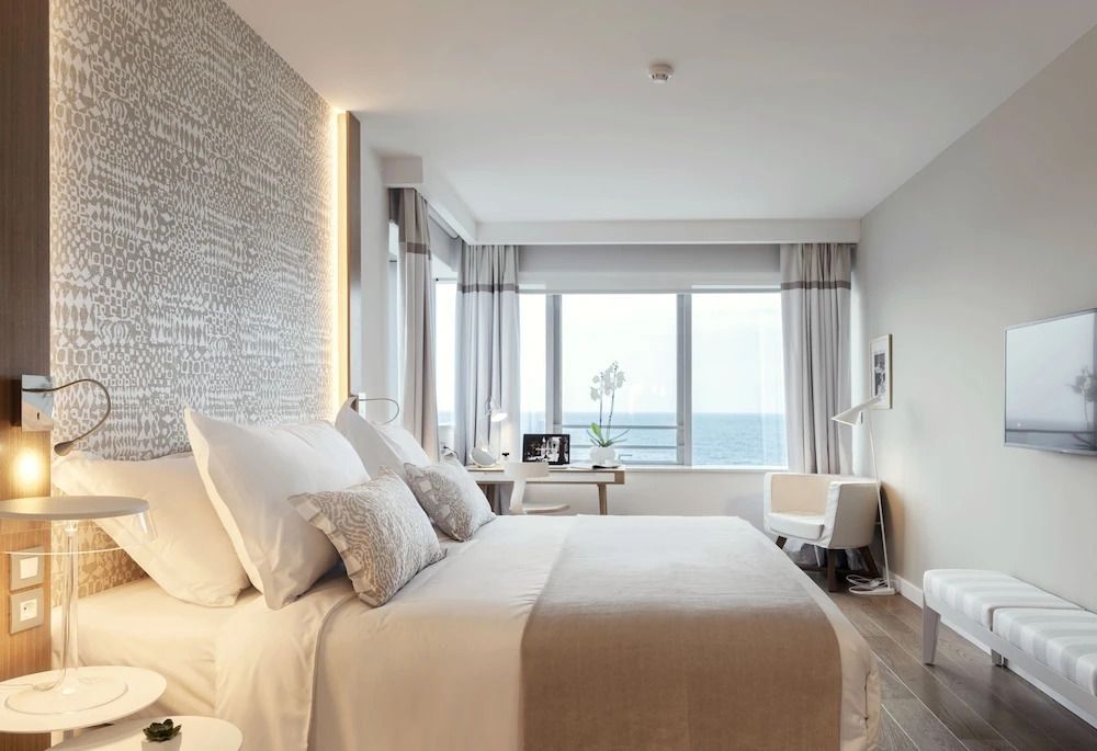 Geräumiges Schlafzimmer mit Kingsize-Bett, stilvollen Kissen und Meerblick durch Fenster