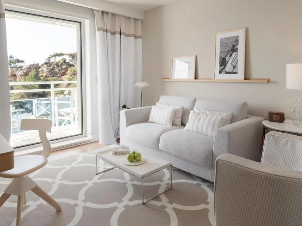 Helles Wohnzimmer mit großem Fenster und Blick auf Balkon in der Vierer Suite