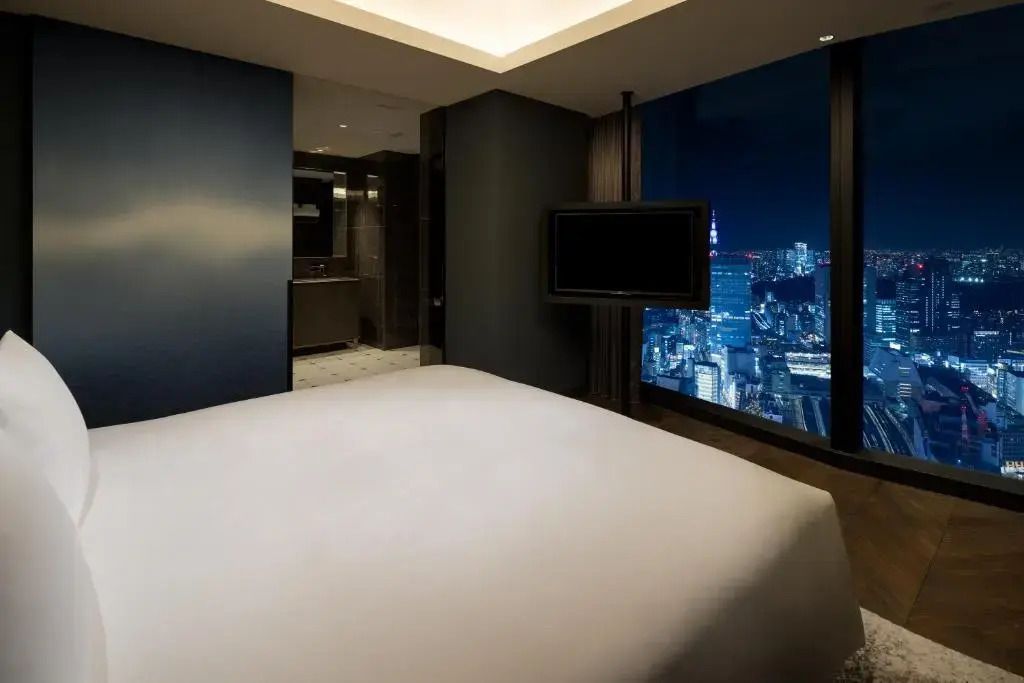 Schlafbereich im Deluxe Studio mit Fensterblick auf die beleuchtete Stadt