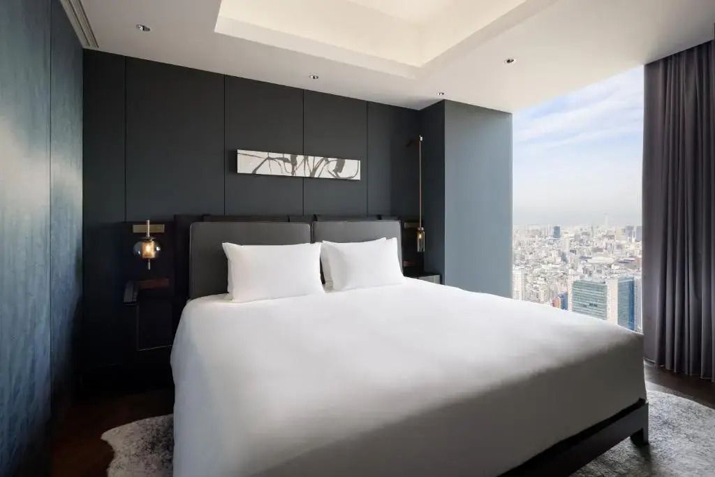 Helles Schlafzimmer mit großem Fenster und Blick über die Stadt