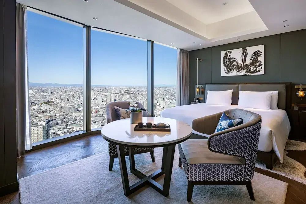 Modernes Hotelzimmer mit Doppelbett und weitem Blick über die Stadt durch große Fenster.