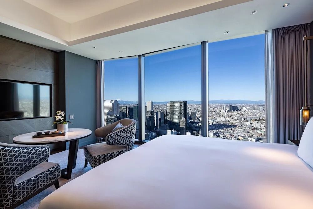 Zimmer mit zwei Sesseln und einem Tisch vor einem Panoramafenster mit Stadtblick.