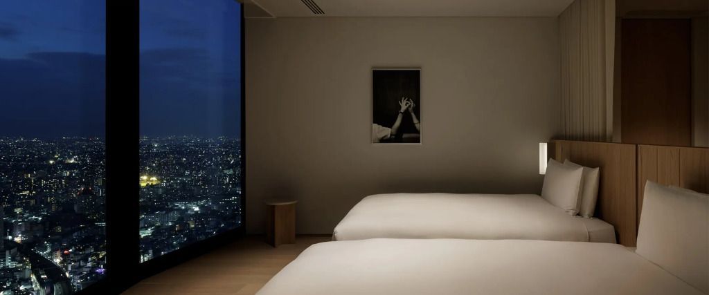 Modernes Hotelzimmer mit zwei Einzelbetten und spektakulärer Aussicht auf die Stadt.