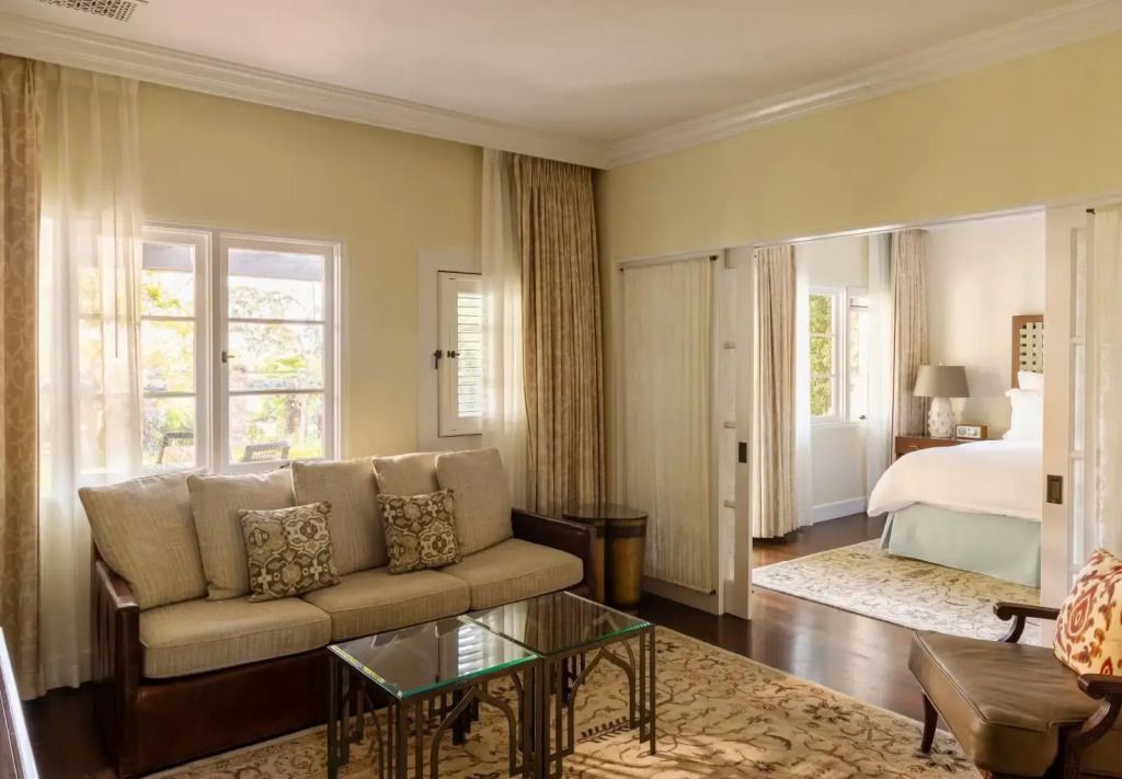 Elegantes Wohnzimmer der Terrace Suite mit Sofa und Glas-Couchtisch vor Fenster.