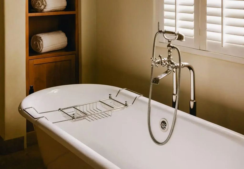 Freistehende Badewanne mit edel verchromter Armatur in luxuriösem Badezimmer.