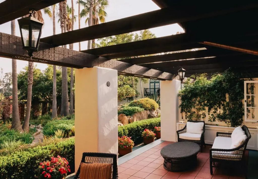 Sonnige Terrasse mit Pergola und bequemen Sitzmöbeln im Garten.