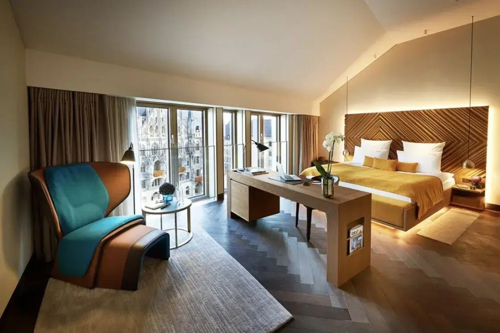 Luxuriöse Suite mit Schreibtisch und Doppelbett vor großen Fenstern
