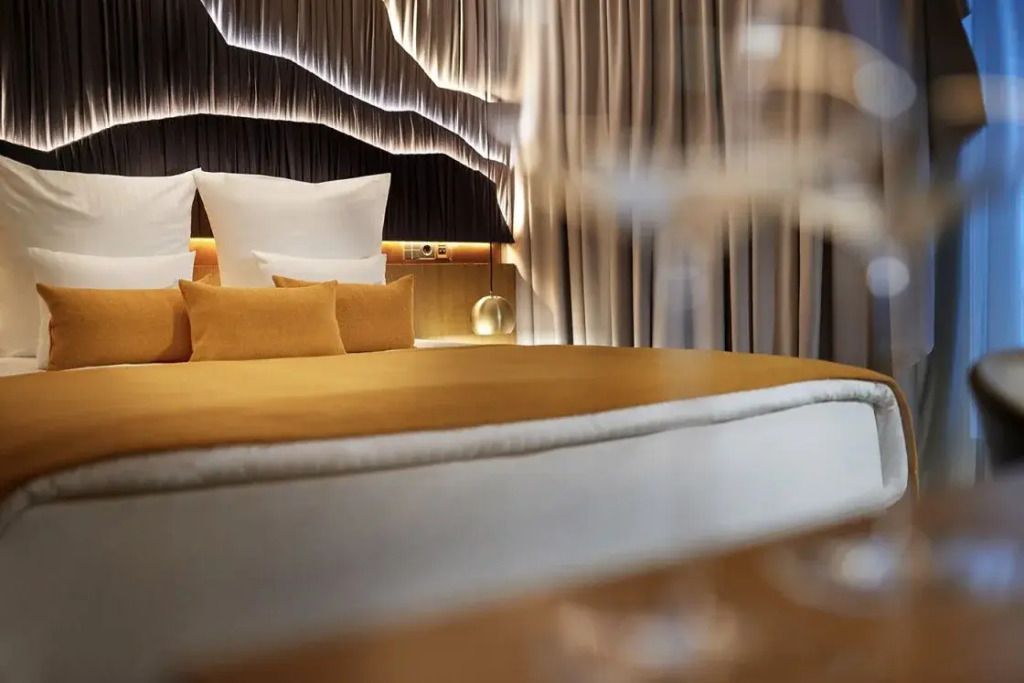 Elegantes Doppelbett mit weichen Kissen und geschwungenem Wanddesign im Hotelzimmer.