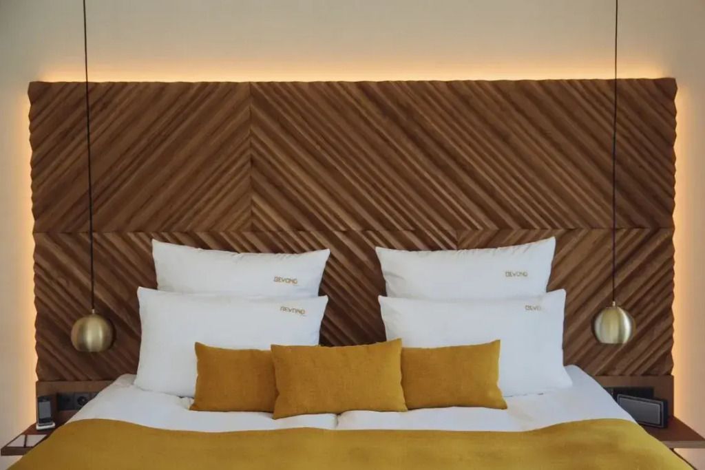 Modernes Doppelbett mit Holzwand und senfgelben Kissen im eleganten Zimmer