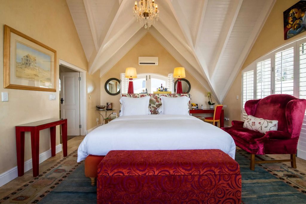 Elegantes Schlafzimmer mit Kronleuchter und farbenfrohem Ottomane.