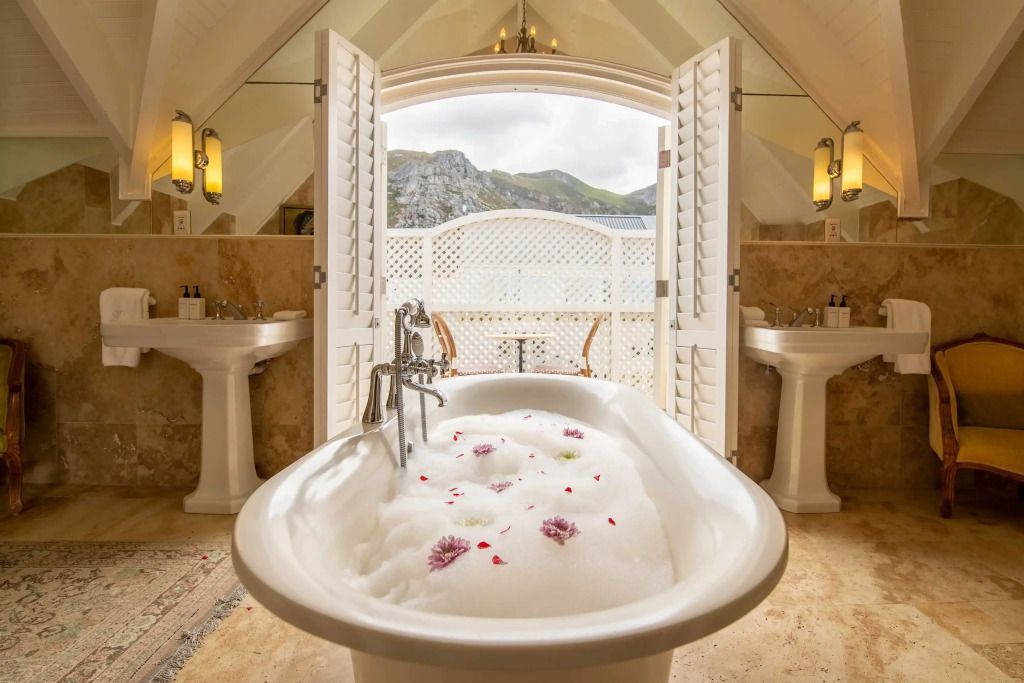 Luxuriöses Badezimmer mit freistehender Badewanne und Ausblick auf die Berge