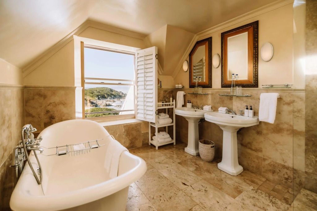 Badezimmer mit freistehender Badewanne, zwei Waschbecken und Fensterblick auf die Landschaft