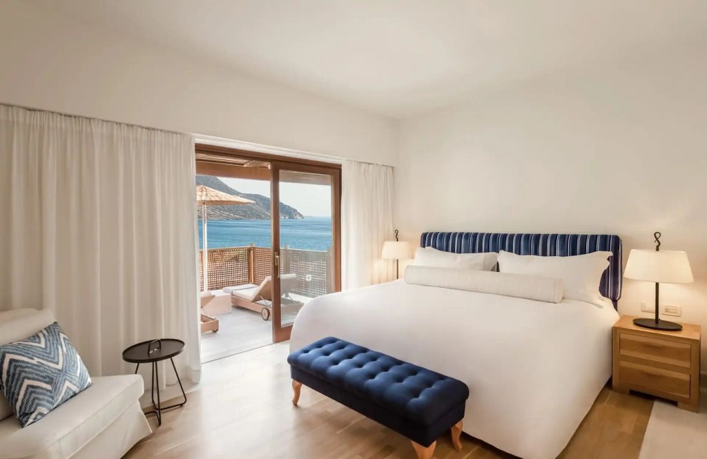 Luxuriöse Suite mit King-Size-Bett und Meerblick auf einen sonnigen Balkon
