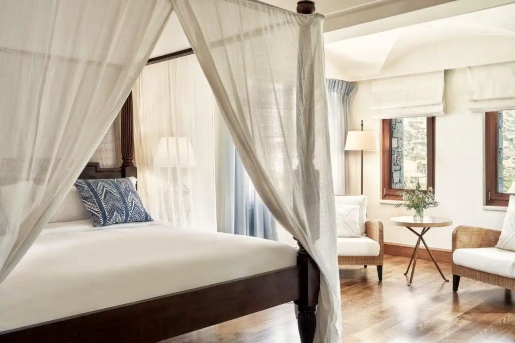 Helles Schlafzimmer mit Himmelbett und gemütlicher Sitzecke am Fenster
