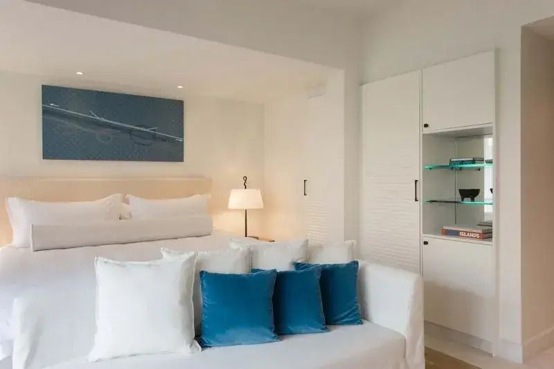 Helles Hotelzimmer mit Doppelbett und blauen Dekokissen