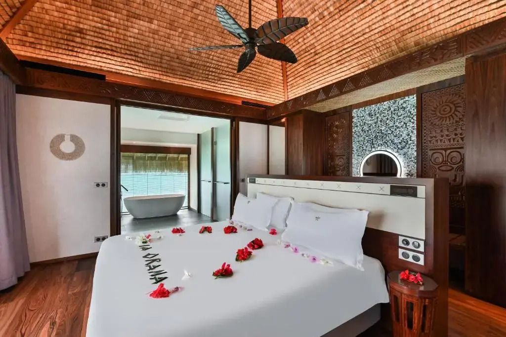Luxuriöses Schlafzimmer in Overwater Suite mit Dekoration und Badewanne im Hintergrund