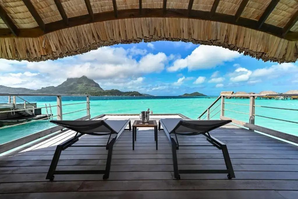 Terrasse eines Überwasser-Bungalows mit Blick auf das türkisfarbene Wasser von Bora Bora.