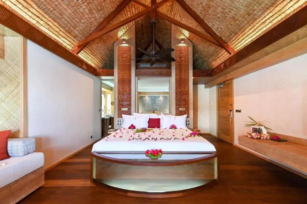 Helles Schlafzimmer im Overwater Bungalow mit Holzbalkendecke und dekorativen Elementen
