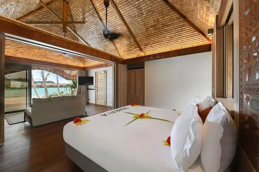 Luxuriöses Schlafzimmer mit Blick auf das Meer und dekorativen Blüten auf dem Bett.