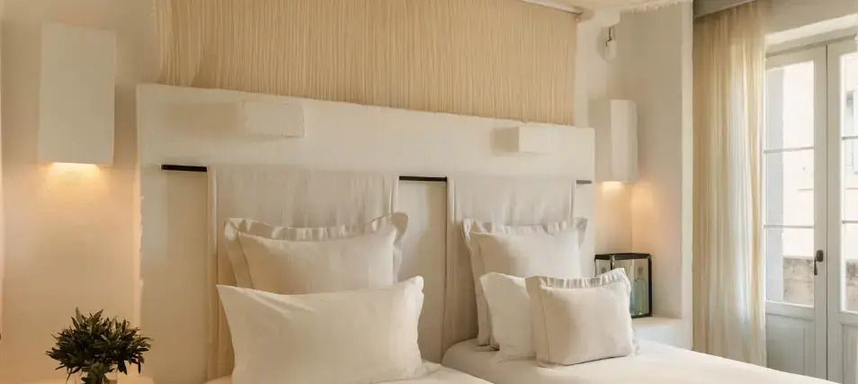 Zwei Betten mit luxuriöser weißer Bettwäsche in einem stilvoll eingerichteten Zimmer