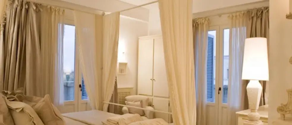 Elegantes Hotelzimmer mit cremefarbenen Vorhängen und gemütlicher Beleuchtung