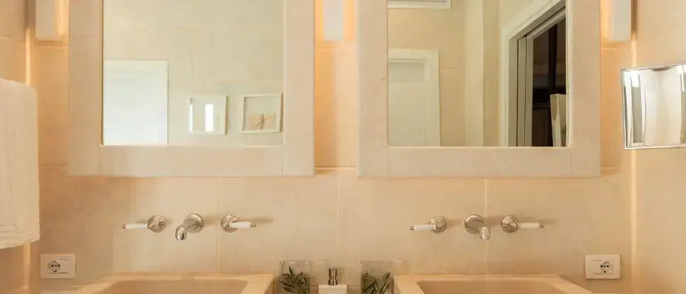 Modernes Badezimmer mit zwei Waschbecken, großen Spiegeln und dezenter Dekoration.