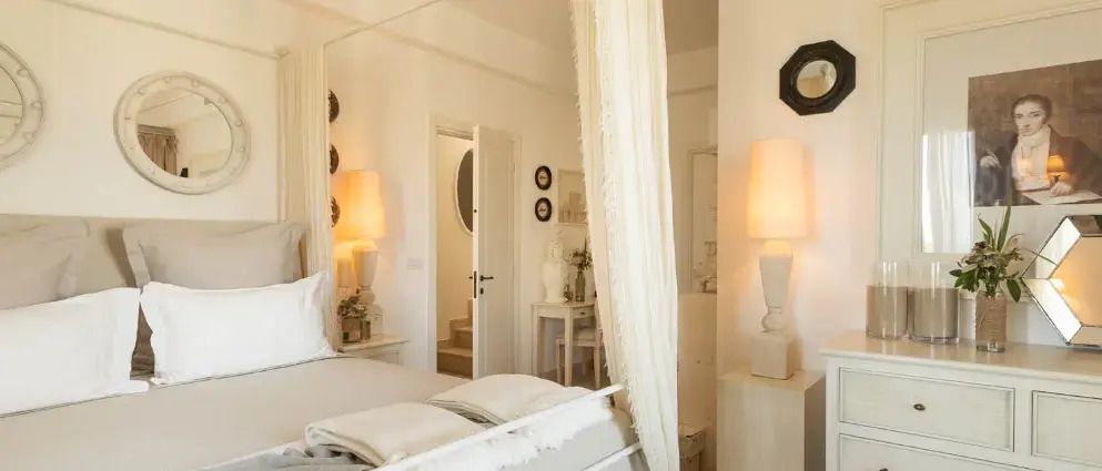 Stilvoll dekoriertes Schlafzimmer mit heller Bettwäsche und sanfter Beleuchtung