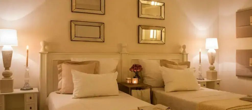 Elegantes Schlafzimmer mit zwei Betten, beiger Dekor und Kerzenlicht.