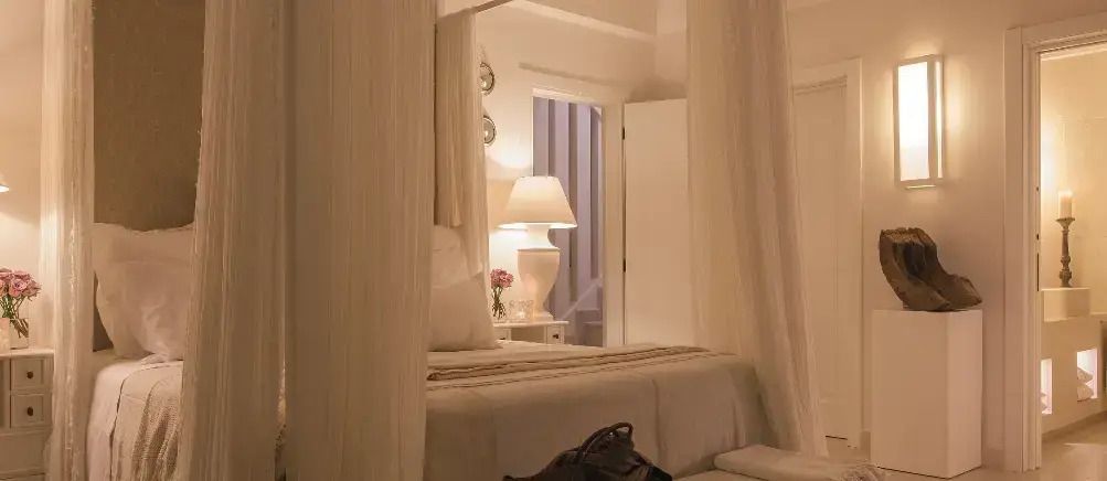 Schlafzimmer mit Baldachinbett, warmem Licht und dezenter Dekoration.