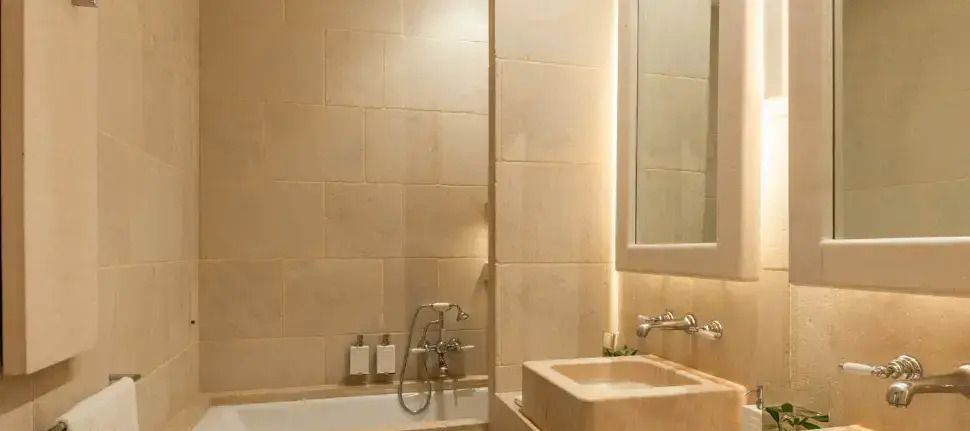 Modernes Bad mit beiger Fliesenverkleidung und stilvollem Waschbecken mit Beleuchtung