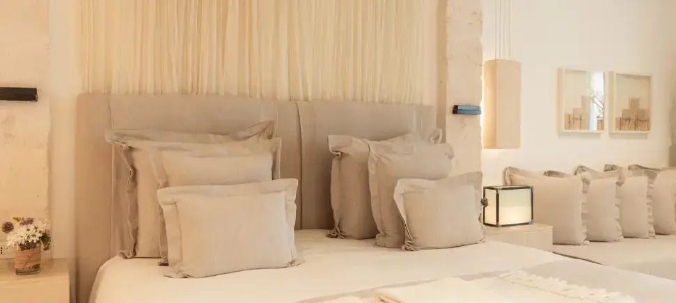 Luxuriöses Doppelbett mit mehreren Kissen und kunstvoller Kopfteilgestaltung
