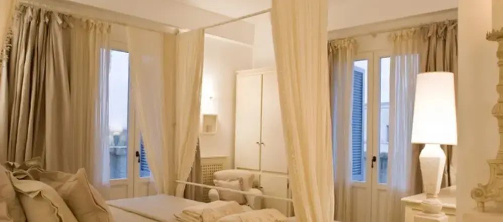 Helles Schlafzimmer mit elegantem Himmelbett und Vorhängen in neutralen Tönen